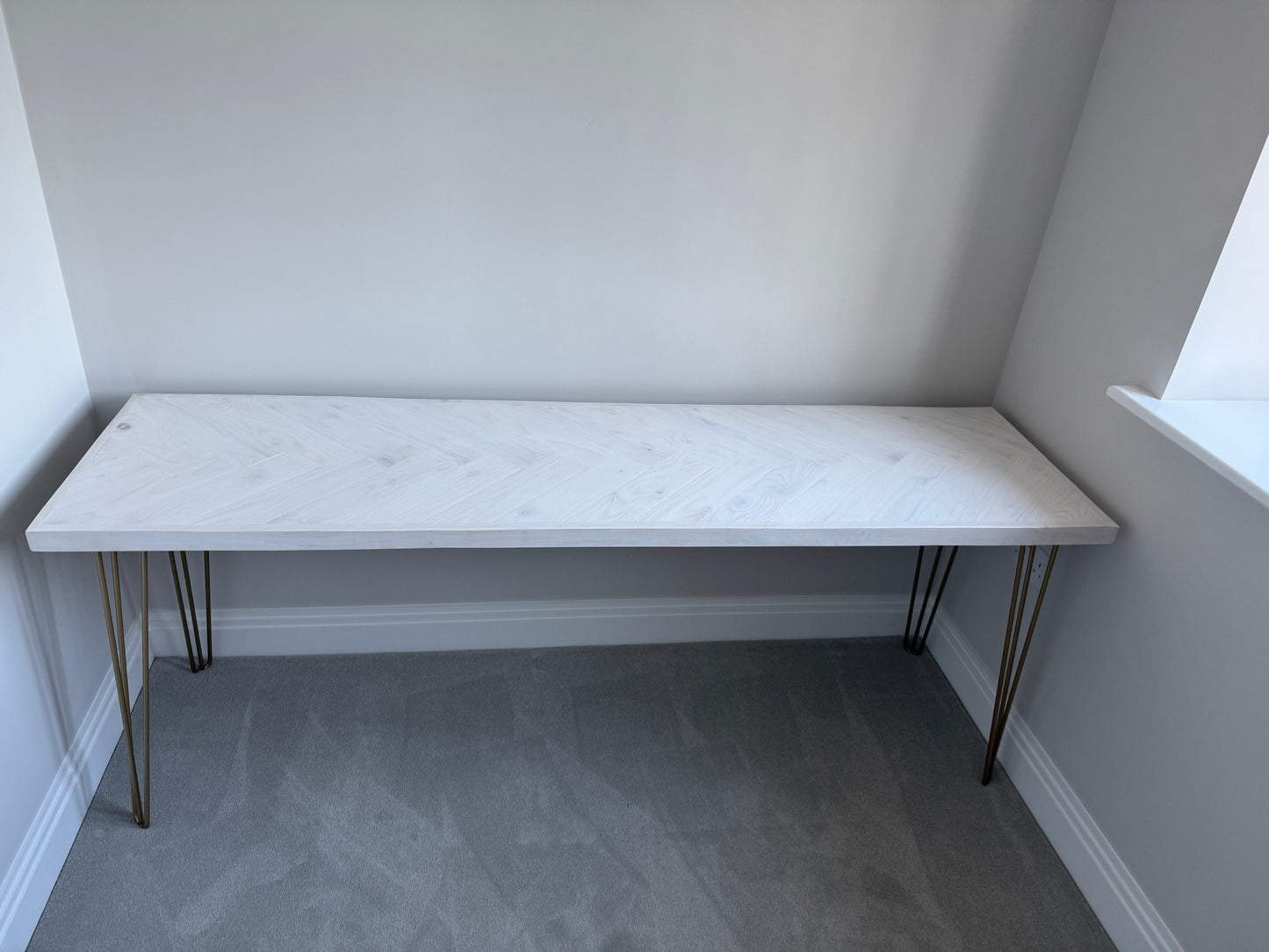 Reclaimed wood desk with herringbone top and black industrial metal legs, featuring a smooth wax finish and natural wood variations