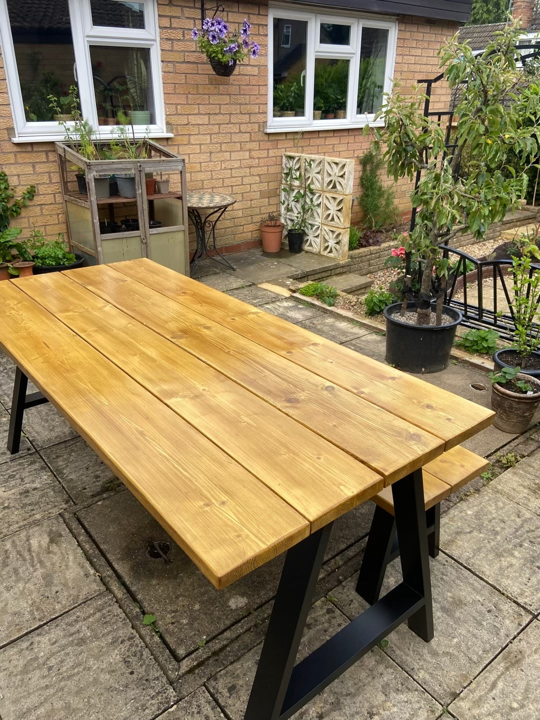 Wooden outdoor table with black legs in a garden setting