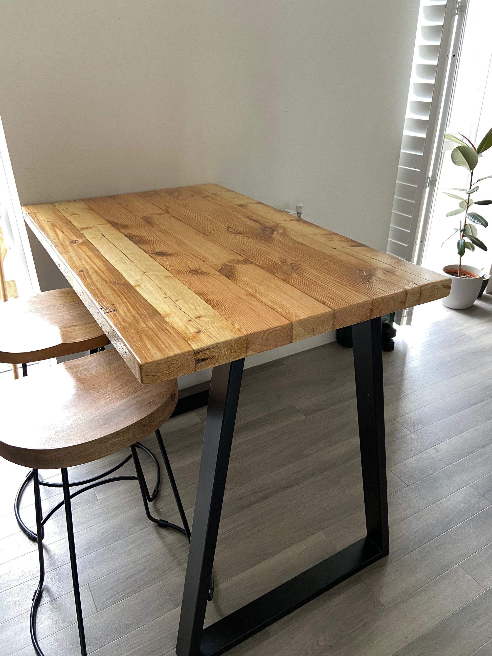 Handcrafted reclaimed wood breakfast bar made from aged joists, featuring natural imperfections, a smooth wax finish, and 90cm high industrial metal legs