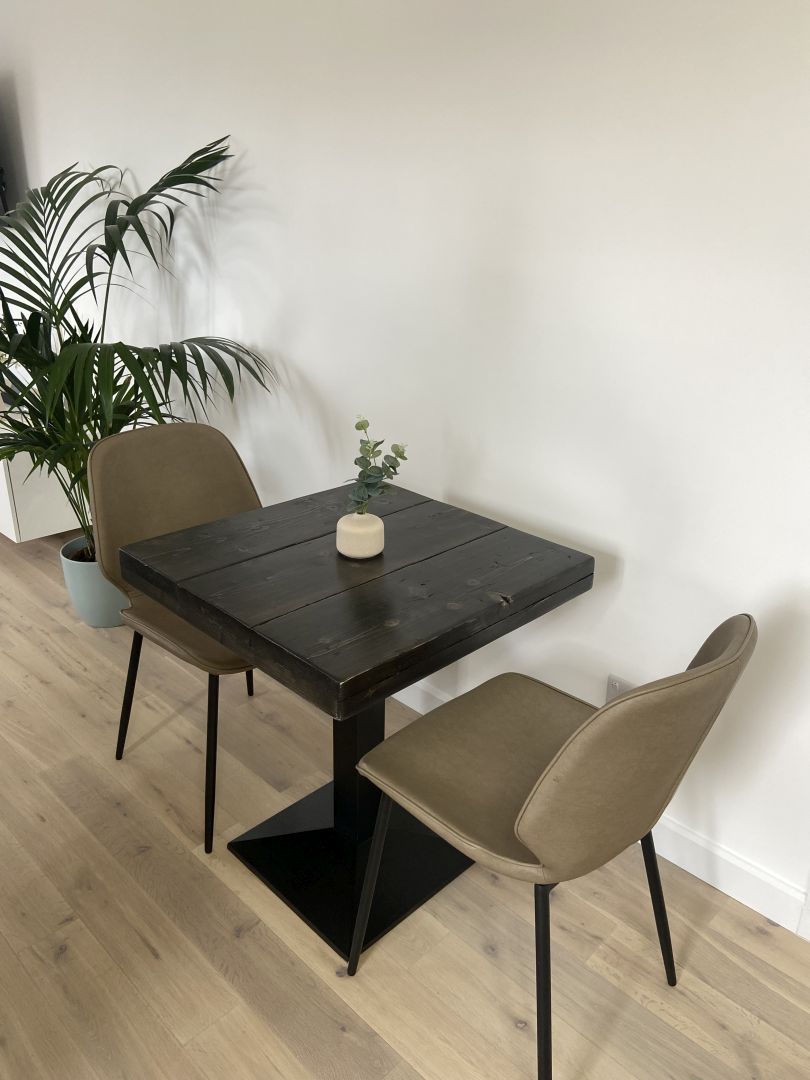 Square bistro table with reclaimed scaffold board top and black cast iron pedestal base, handcrafted in the UK with a smooth wax finish