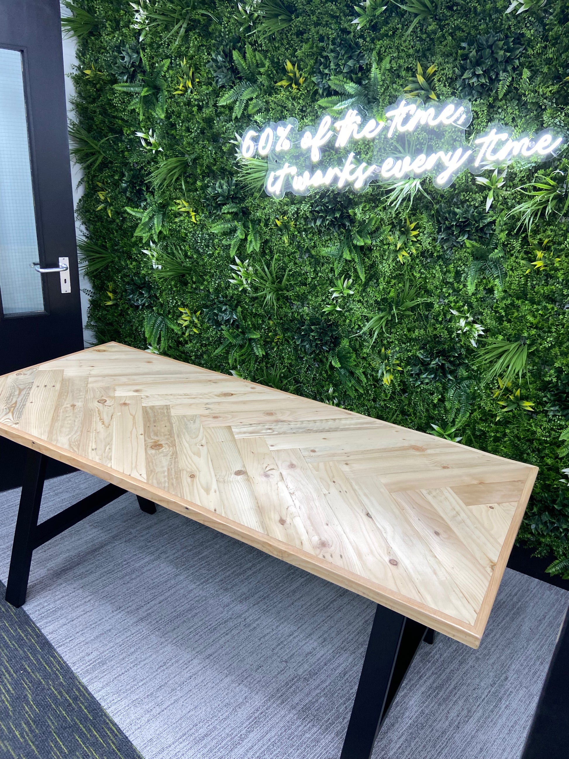 Reclaimed wood desk with herringbone top and black industrial metal legs, featuring a smooth wax finish and natural wood variations
