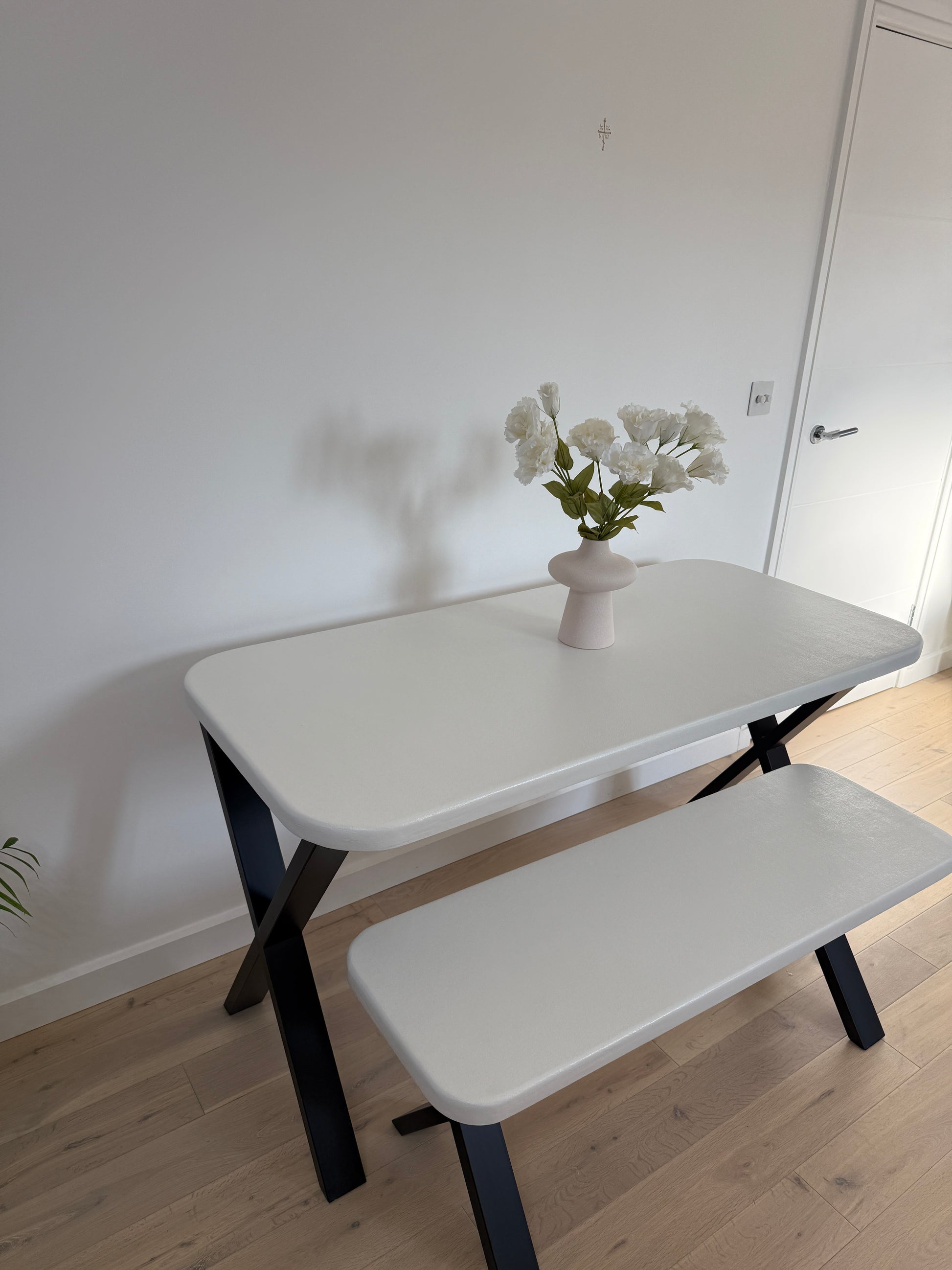 Handmade microcement dining table with white concrete-style top and matching benches, black metal legs – made to order in the UK.