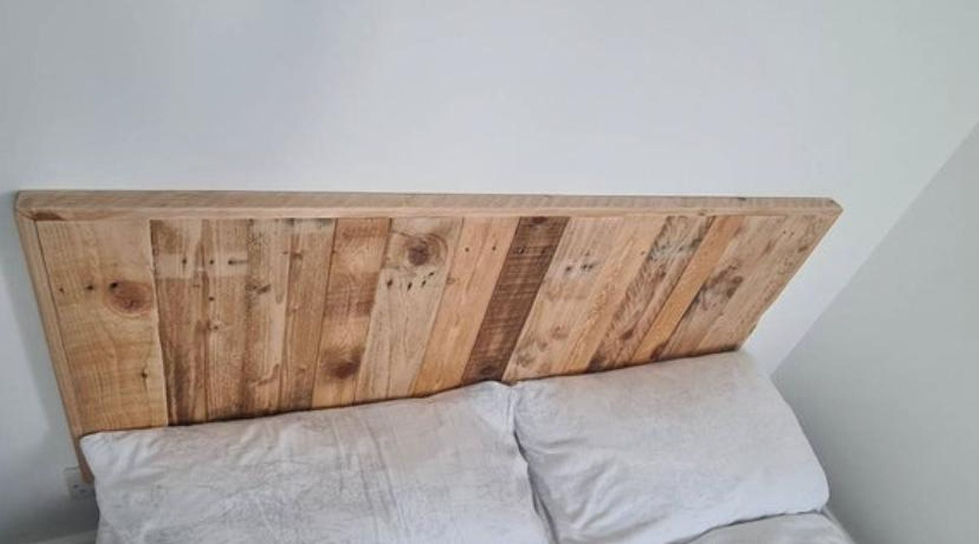 Wall-mounted headboard made from reclaimed wood planks with natural rustic finish – handmade and eco-friendly design