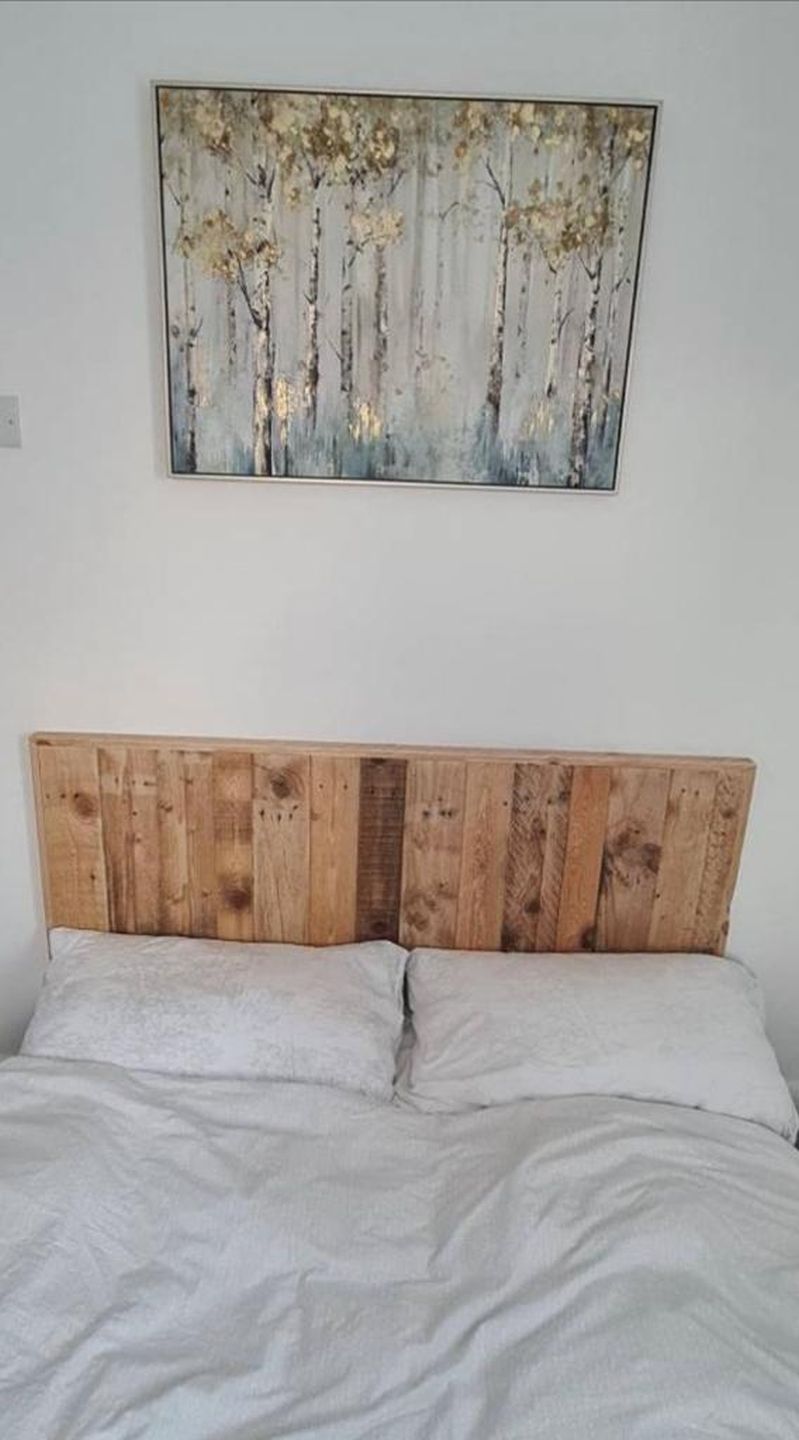 Wall-mounted headboard made from reclaimed wood planks with natural rustic finish – handmade and eco-friendly design