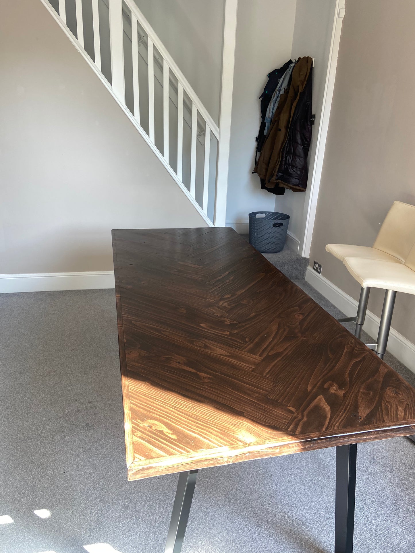 Reclaimed wood desk with herringbone top and black industrial metal legs, featuring a smooth wax finish and natural wood variations