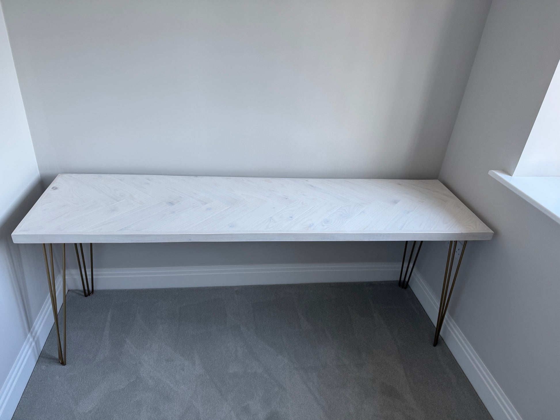 Reclaimed wood desk with herringbone top and black industrial metal legs, featuring a smooth wax finish and natural wood variations