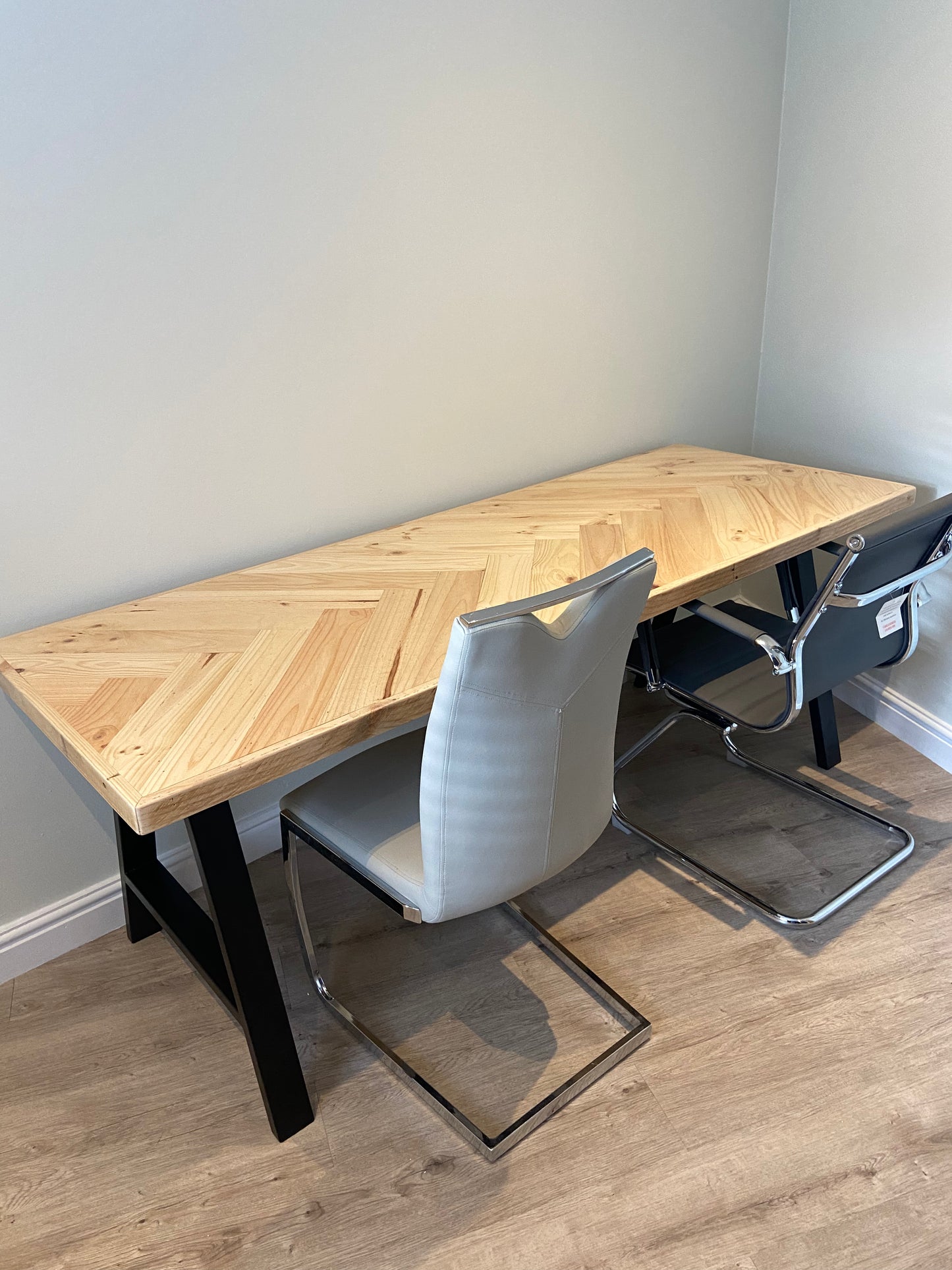 Reclaimed wood desk with herringbone top and black industrial metal legs, featuring a smooth wax finish and natural wood variations