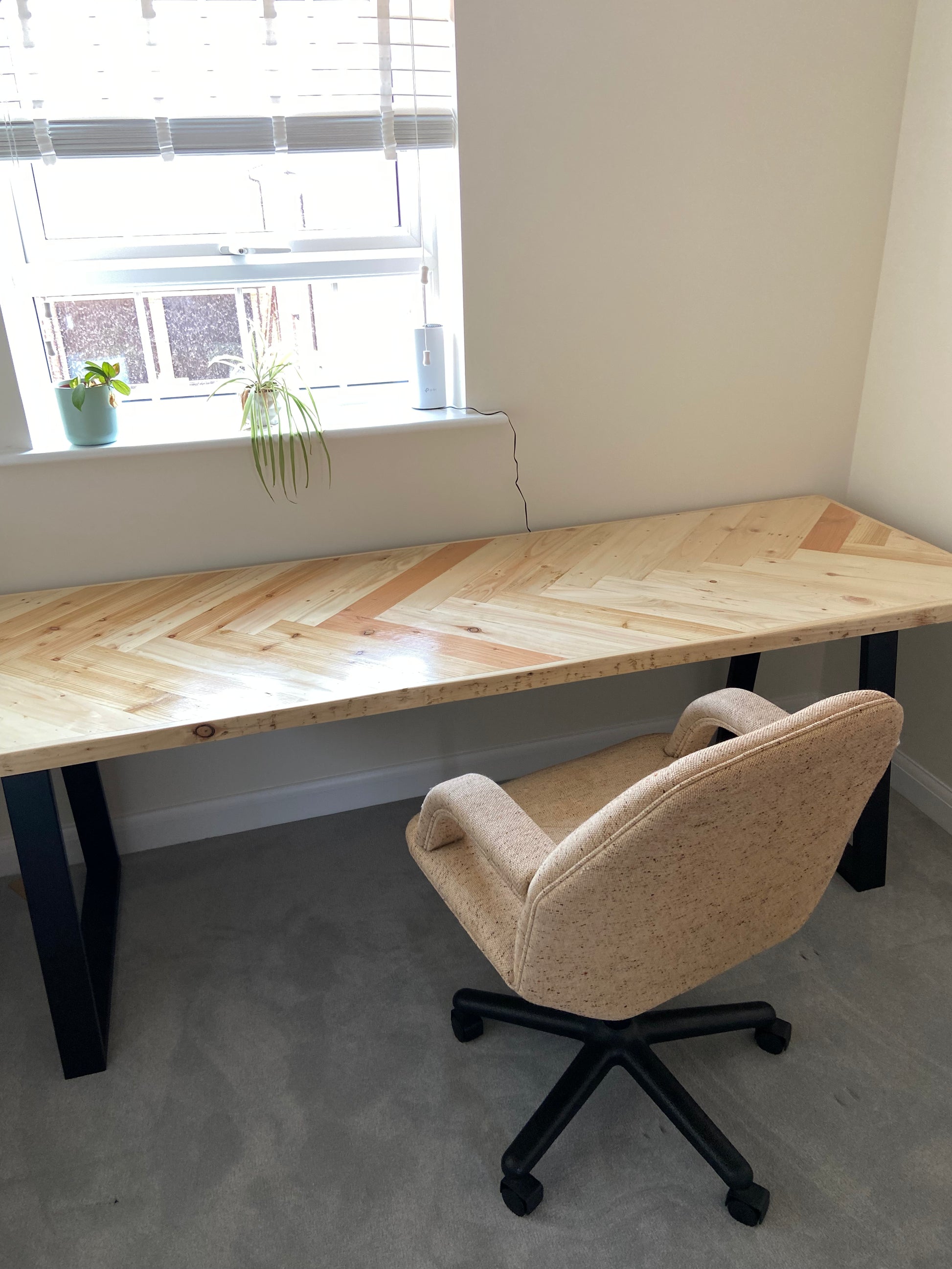Reclaimed wood desk with herringbone top and black industrial metal legs, featuring a smooth wax finish and natural wood variations