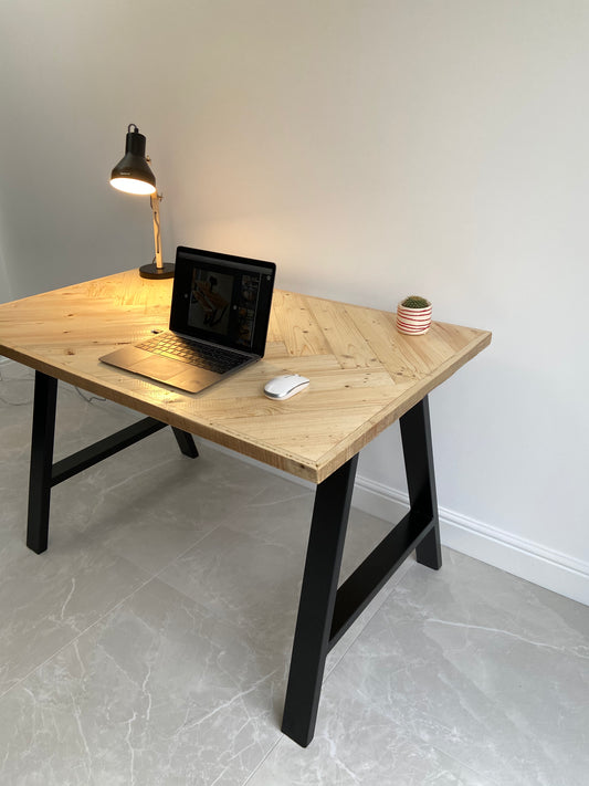 Reclaimed wood desk with herringbone top and black industrial metal legs, featuring a smooth wax finish and natural wood variations