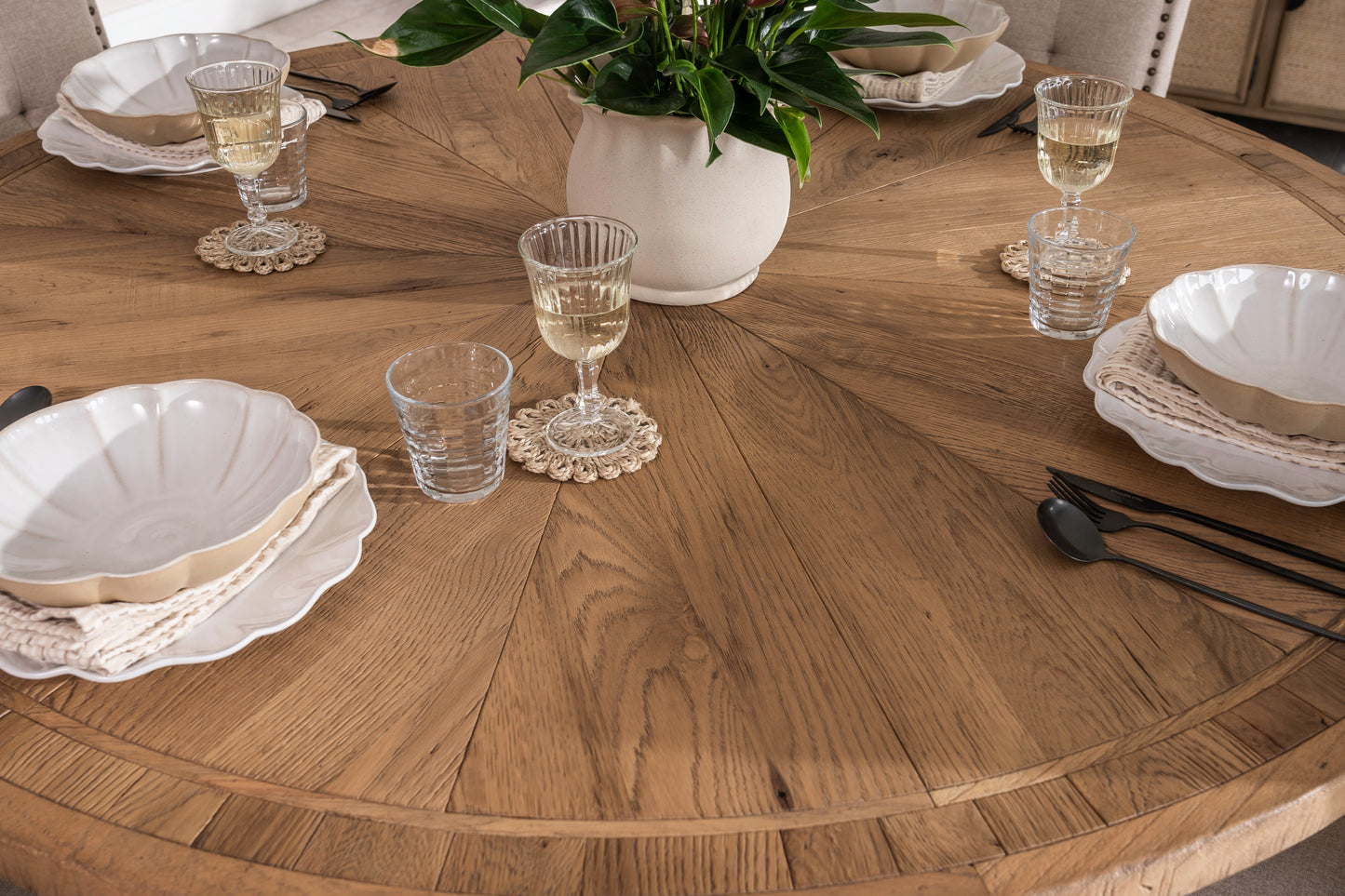 Round solid oak extending dining table in classic farmhouse style, styled in a bright dining area. Part of the Elmstead Series by TheRoughWood.