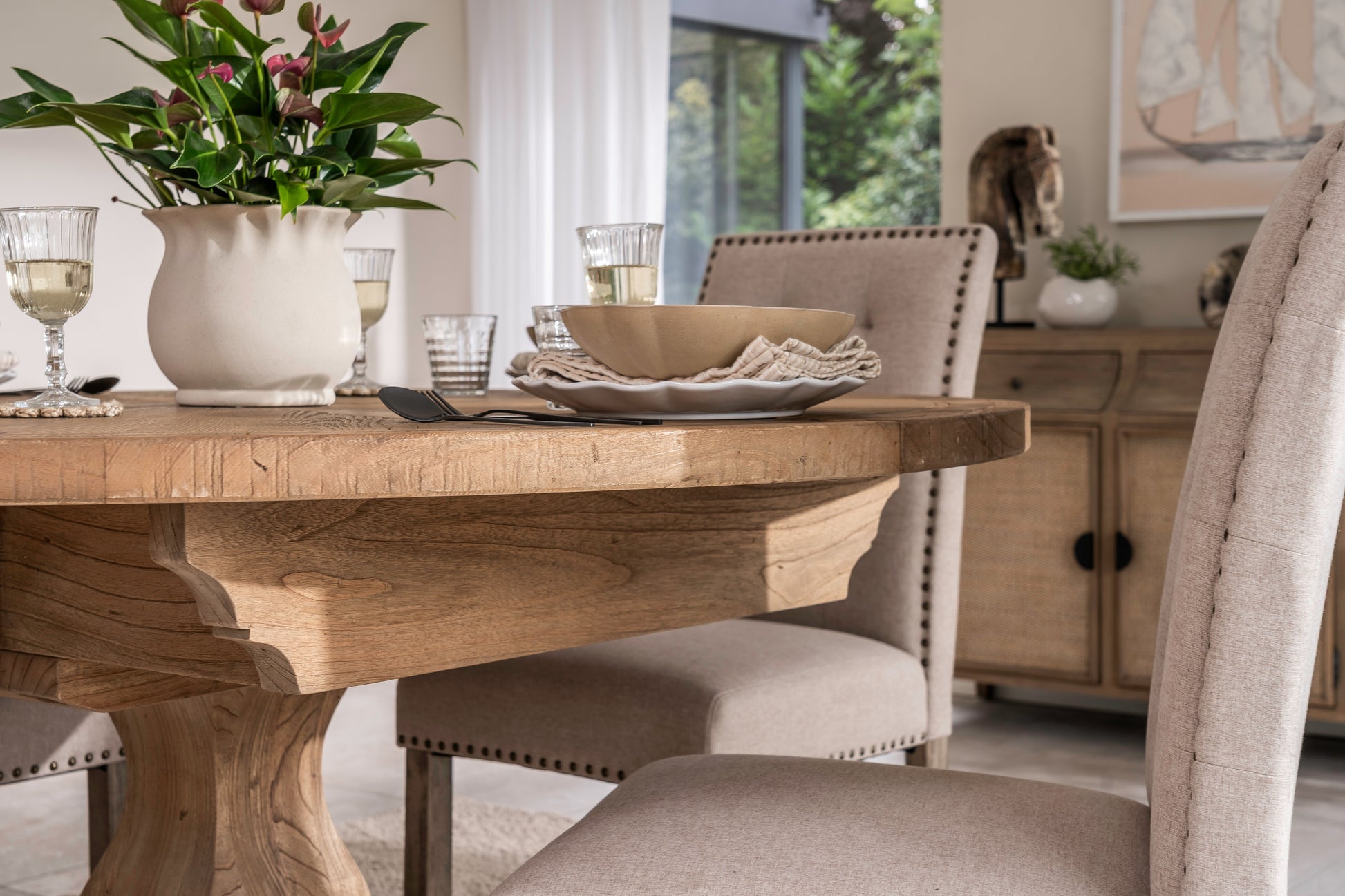 Round solid oak extending dining table in classic farmhouse style, styled in a bright dining area. Part of the Elmstead Series by TheRoughWood.