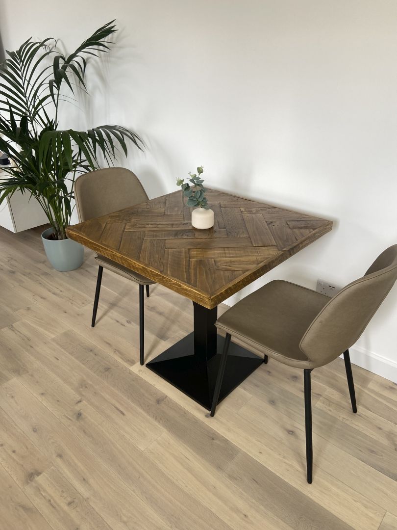 Handmade square bistro table with double herringbone reclaimed wood top and black cast iron pedestal base, finished with natural wax