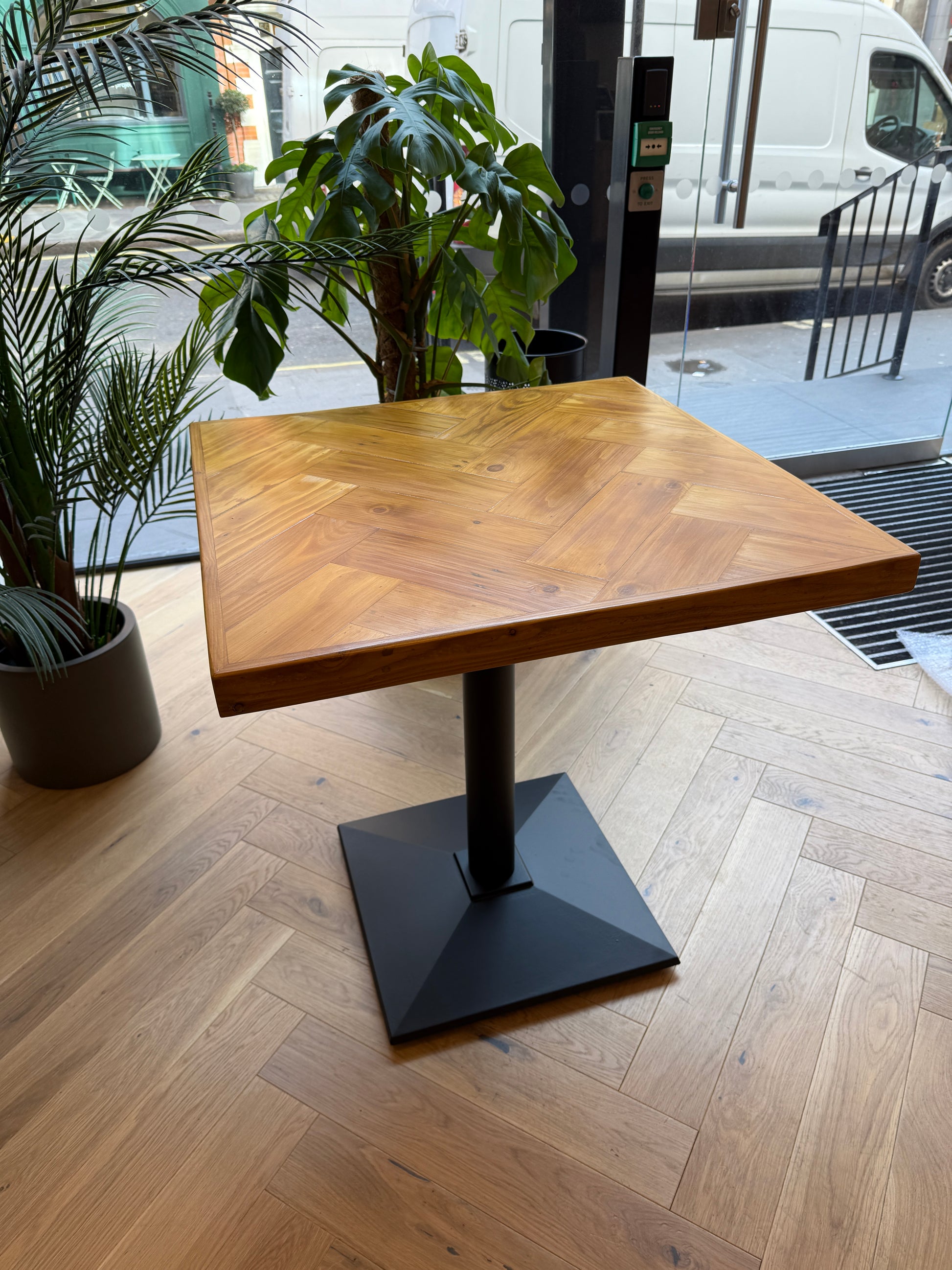 Handmade square bistro table with double herringbone reclaimed wood top and black cast iron pedestal base, finished with natural wax
