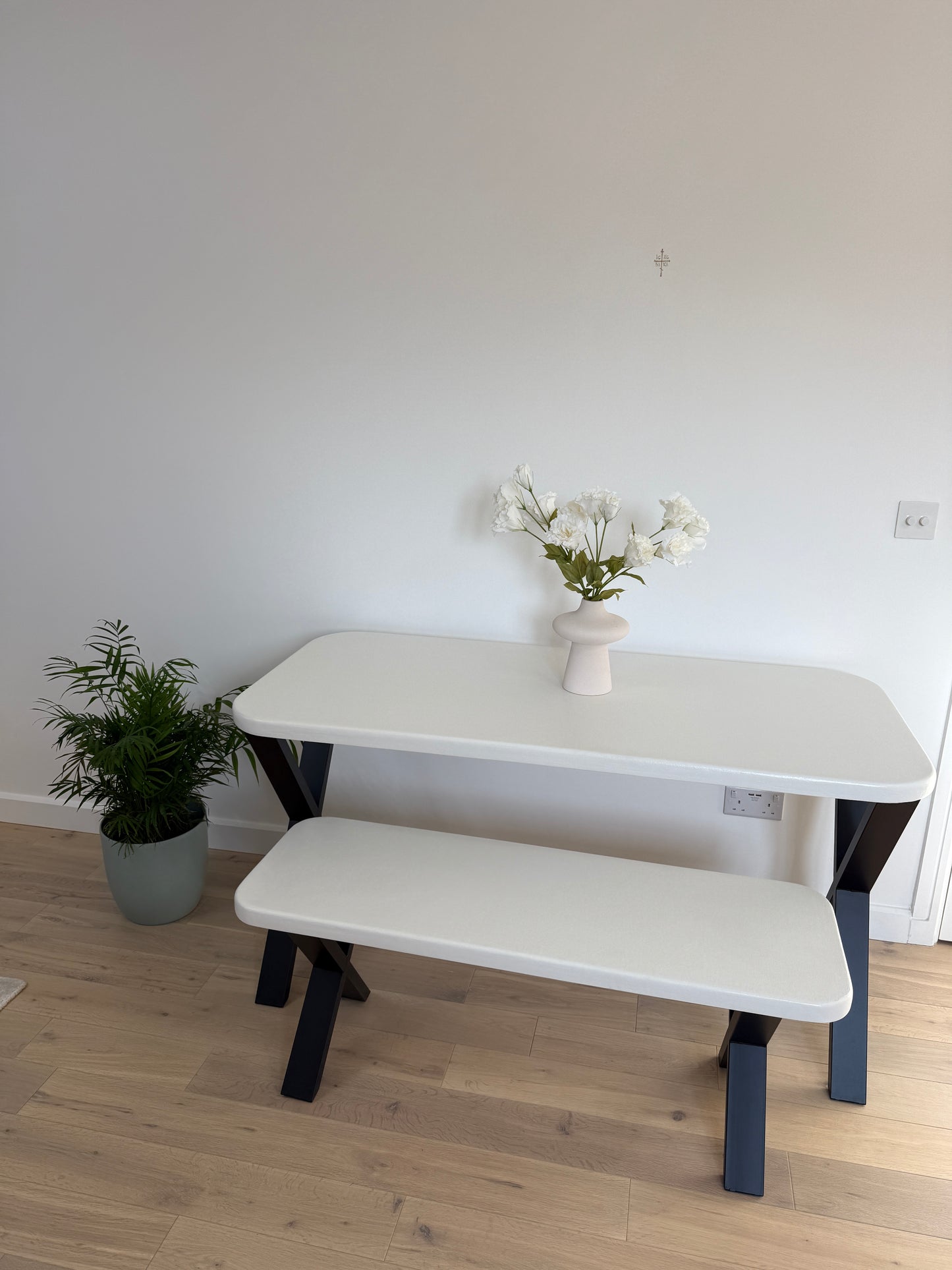 Handmade microcement dining table with white concrete-style top and matching benches, black metal legs – made to order in the UK.
