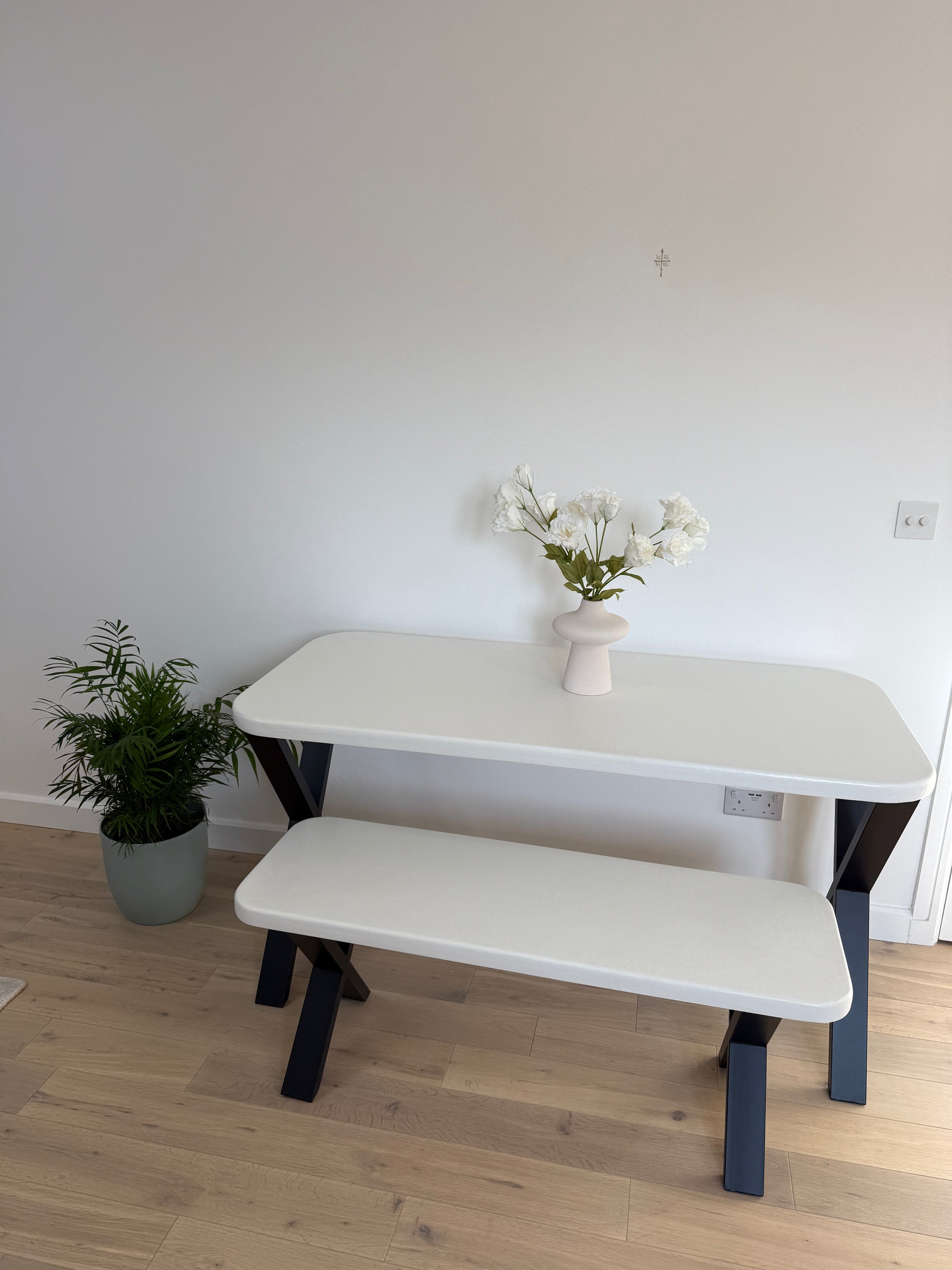 Handmade microcement dining table with white concrete-style top and matching benches, black metal legs – made to order in the UK.