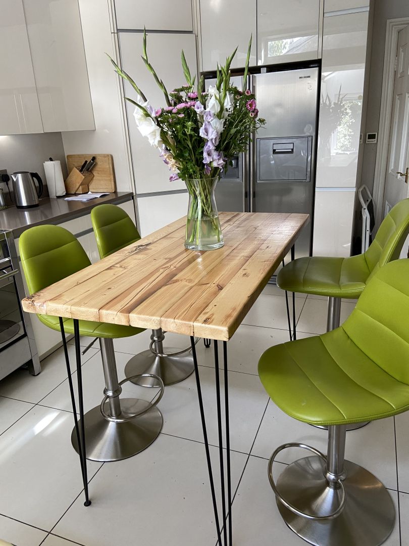 Handcrafted reclaimed wood breakfast bar made from aged joists, featuring natural imperfections, a smooth wax finish, and 90cm high industrial metal legs
