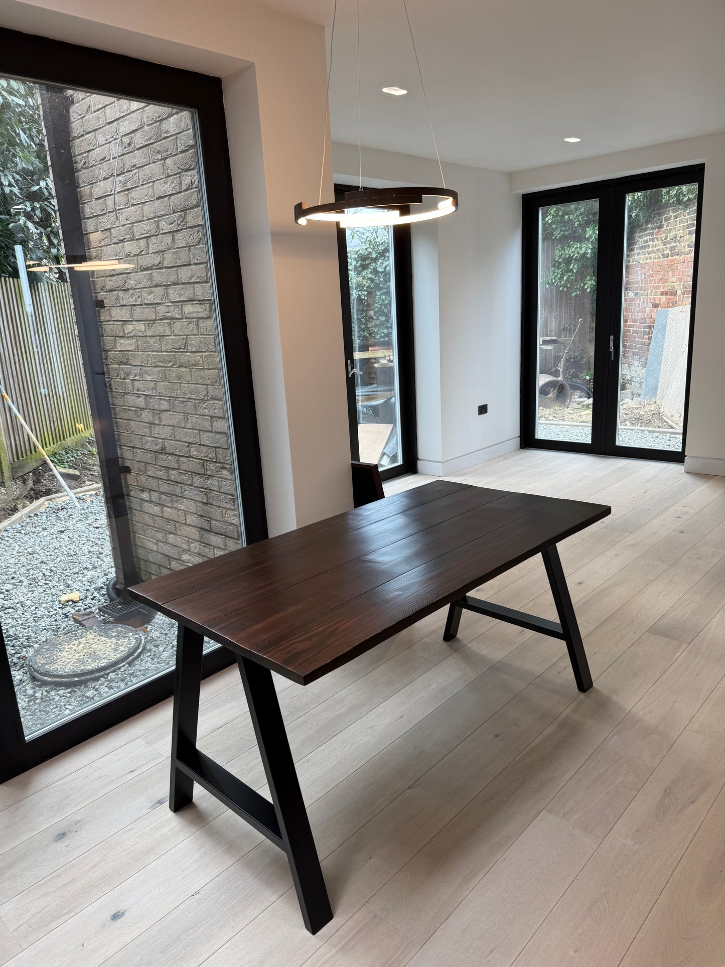 Wooden table and chairs in a modern room with large windows.