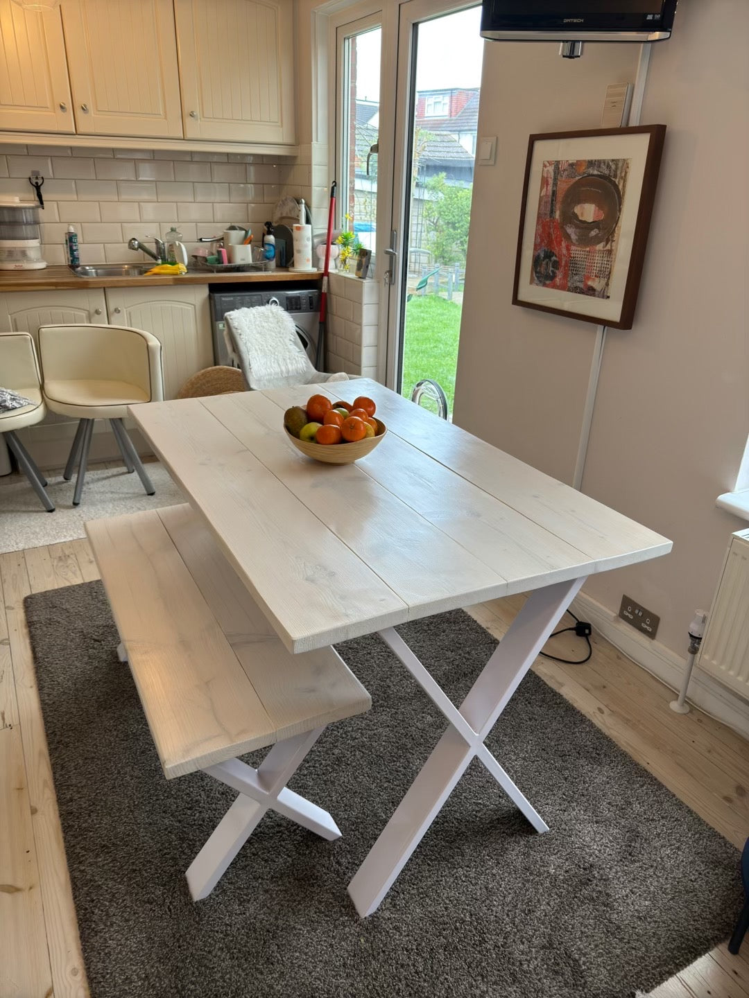 White dining table with bench in a kitchen setting