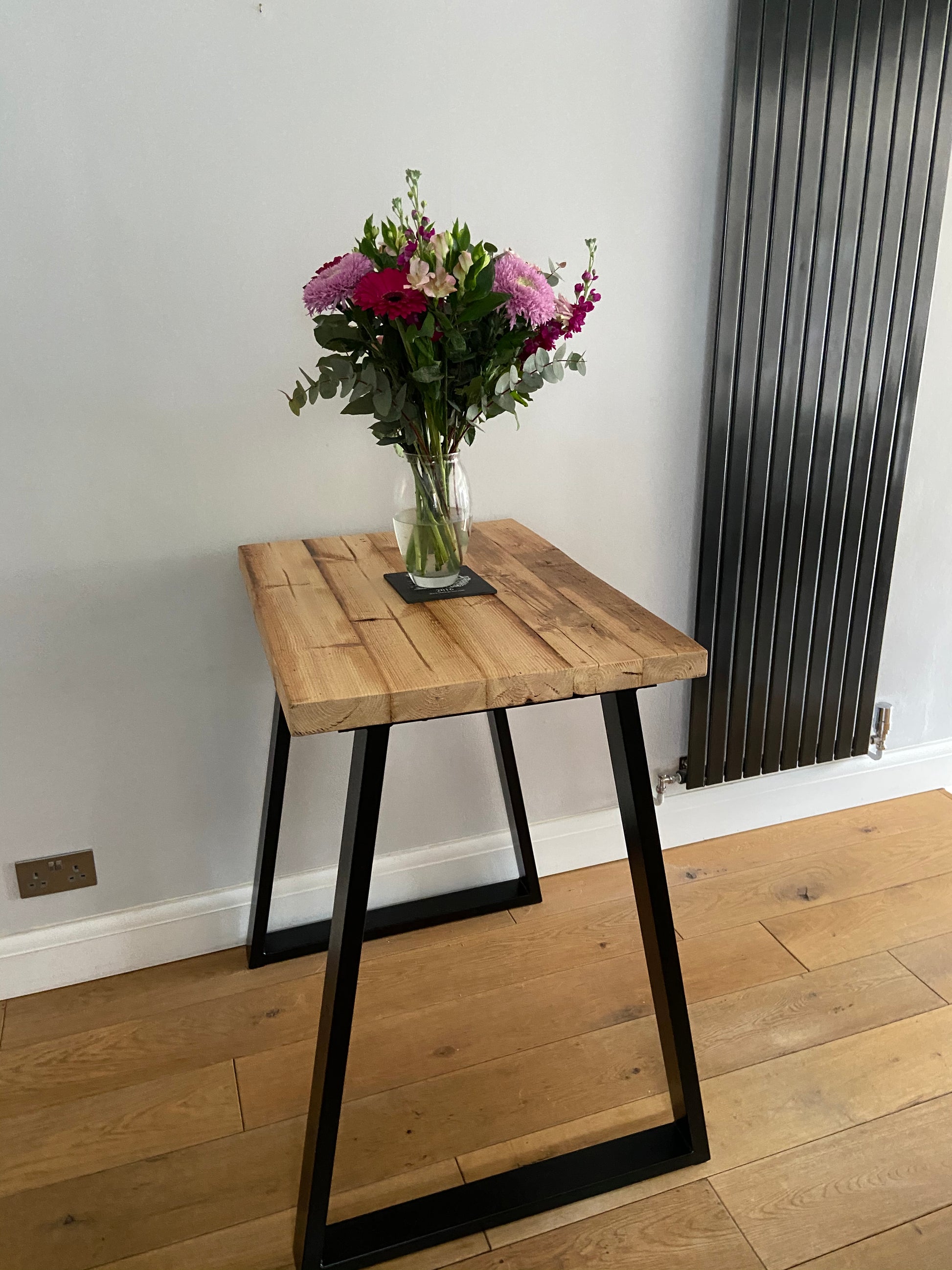 Handcrafted reclaimed wood breakfast bar made from aged joists, featuring natural imperfections, a smooth wax finish, and 90cm high industrial metal legs