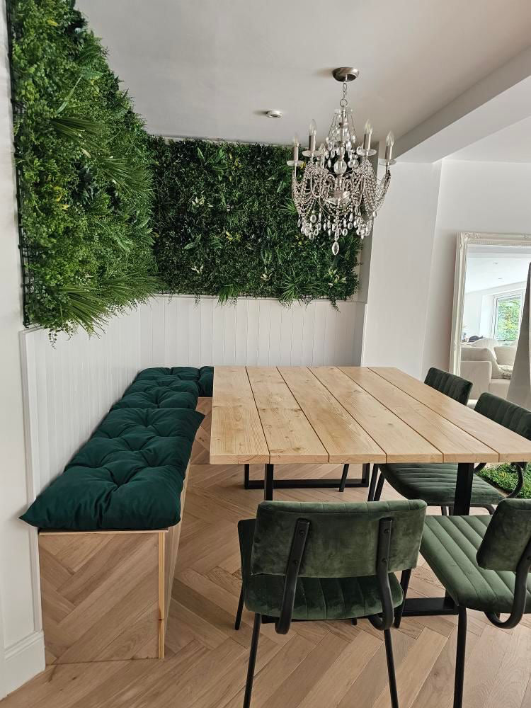 Dining area with wooden table, green cushioned chairs, and a chandelier.