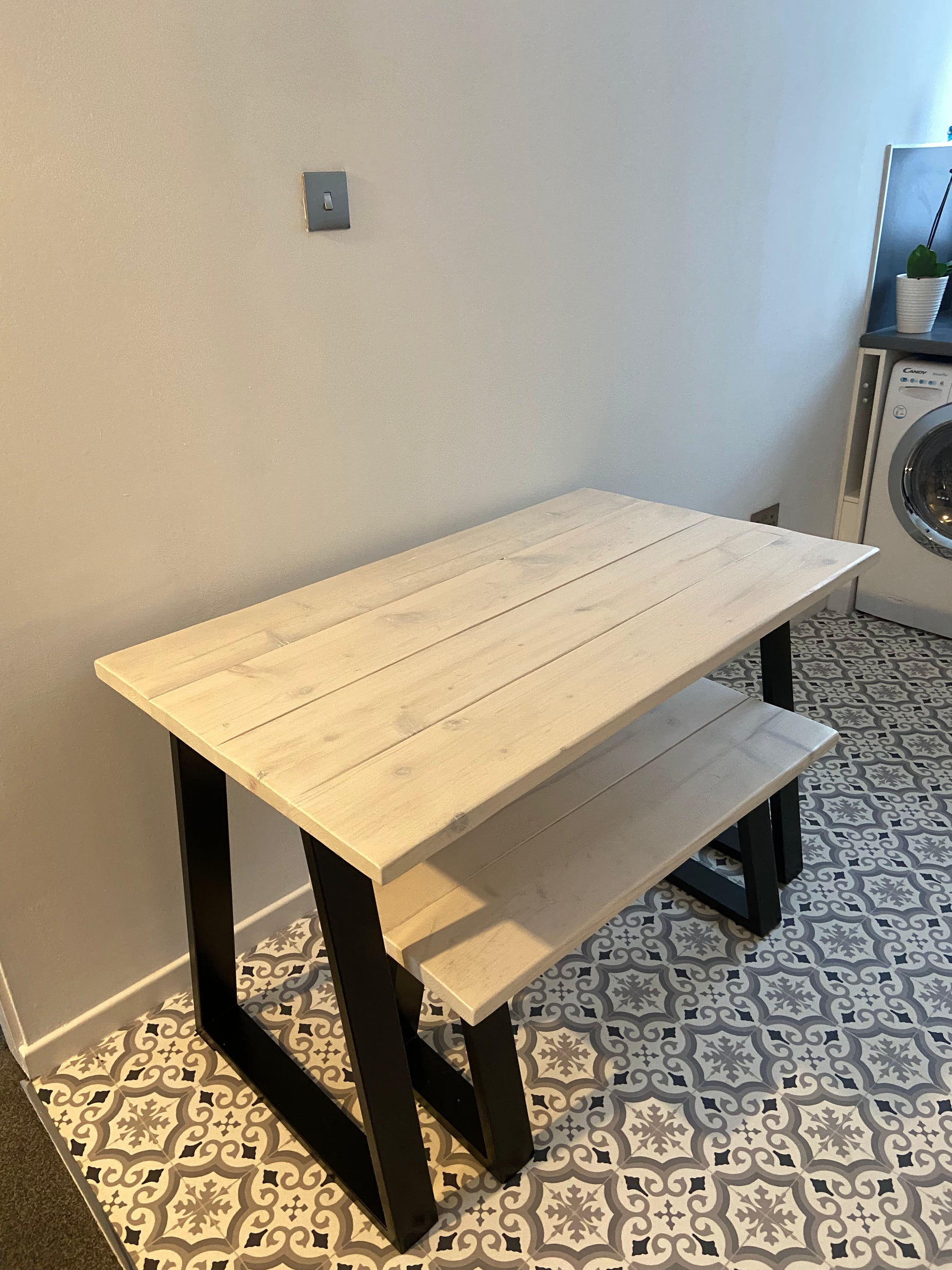 Wooden table with black legs on a patterned floor