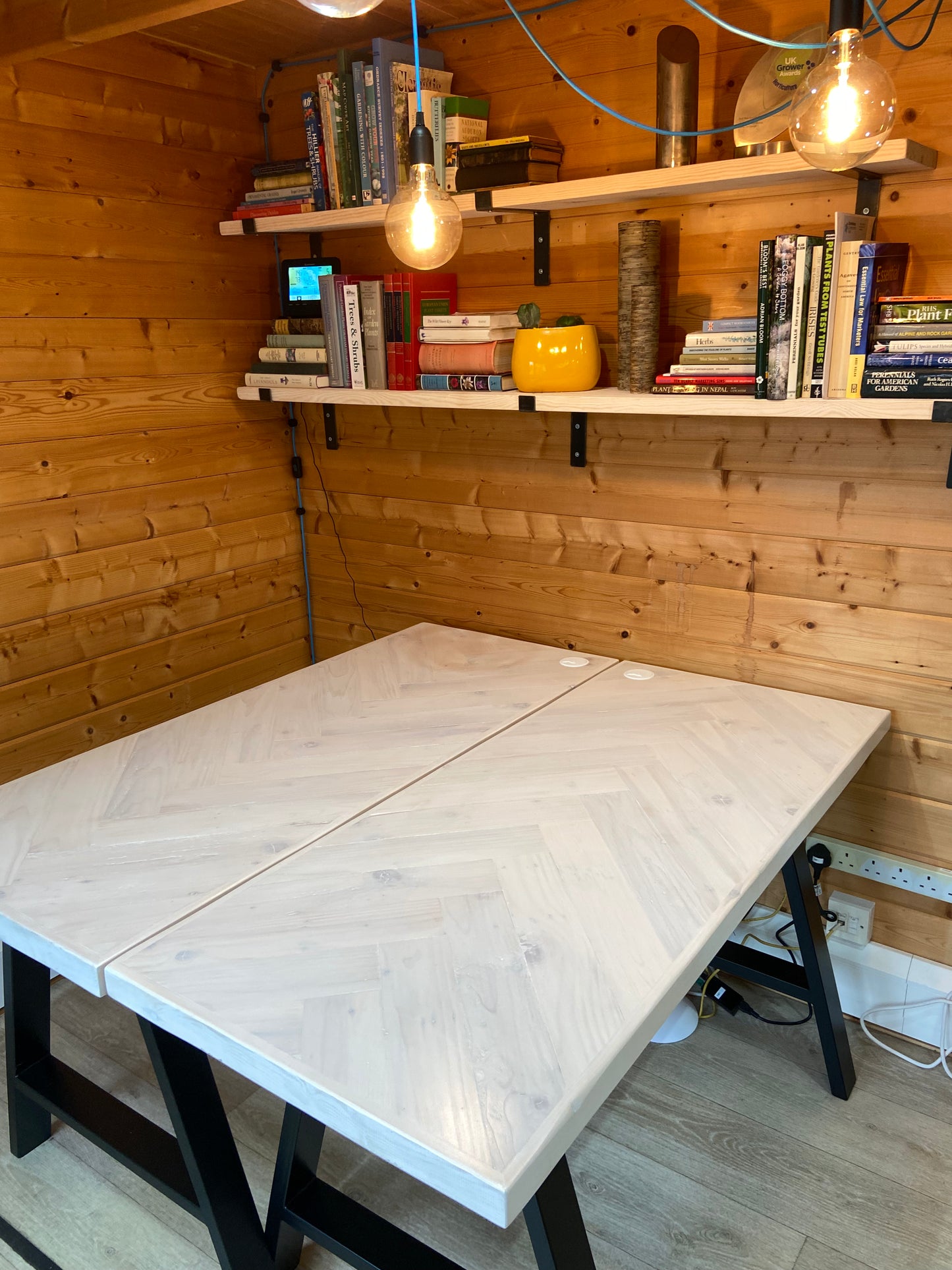 Reclaimed wood desk with herringbone top and black industrial metal legs, featuring a smooth wax finish and natural wood variations
